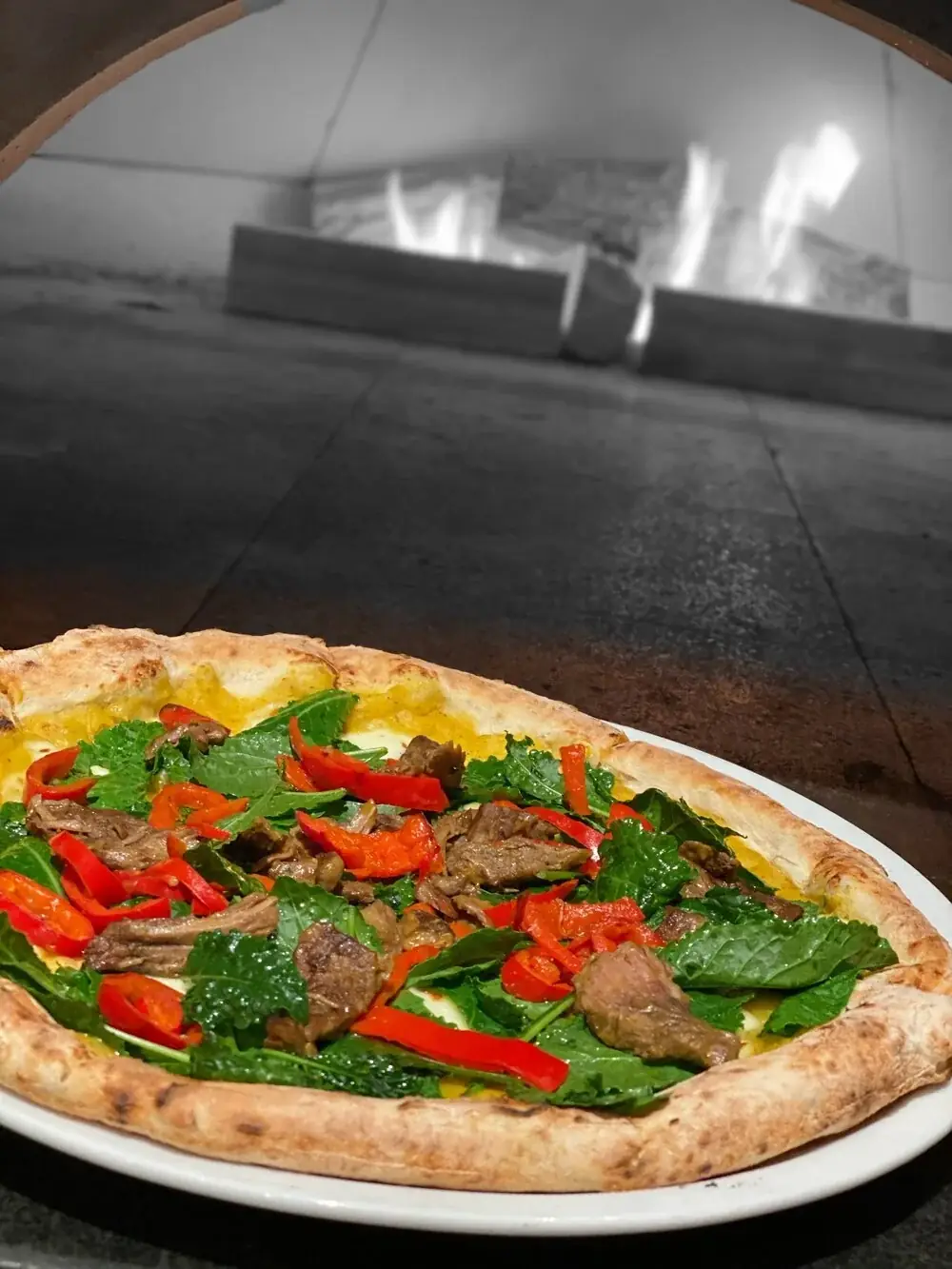 This month we start a puree of Koginut squash, potato and mozzarella cheese. Once cooked, we add baby kale. We then add strips of grilled marinated AAA beef and&nbsp;smokey&nbsp;Fresno Peppers.&nbsp;    This pizza is available with or without the beef.
