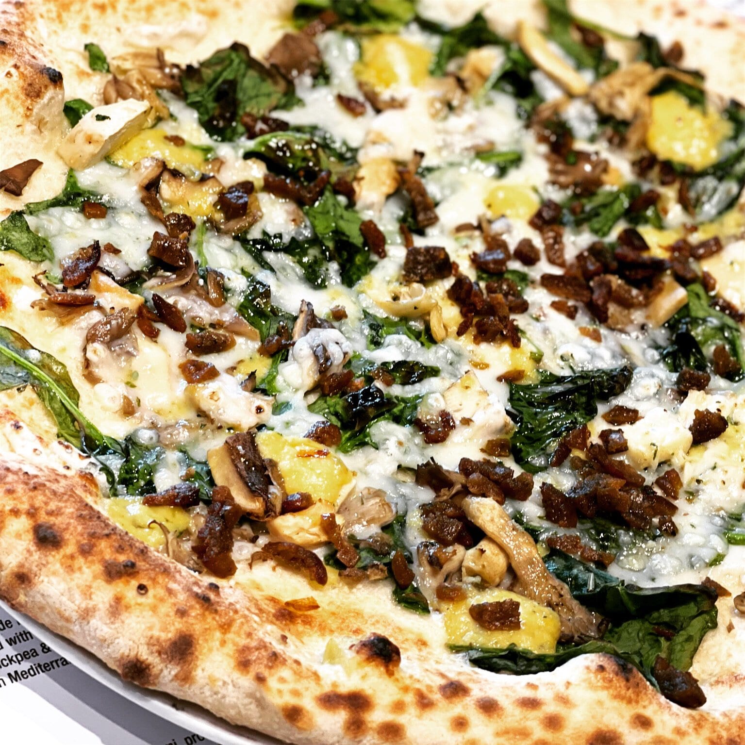 A vegan friendly pizza made up of spinach, deep fried Vegan sausage, wild mushrooms, garlic oil, truffle oil, dairy-free mozzarella and truffle cheese ($18.25).